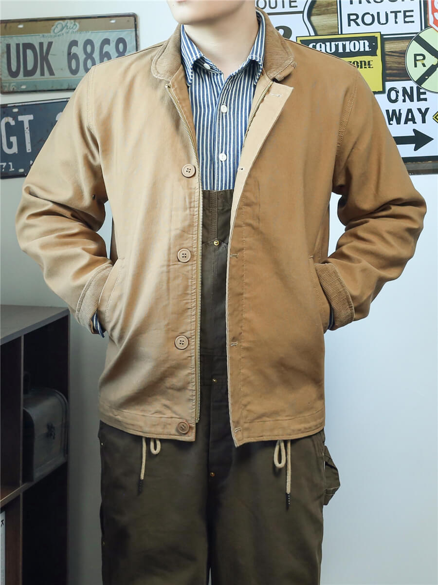 Person wearing a tan jacket over a striped shirt with a white background